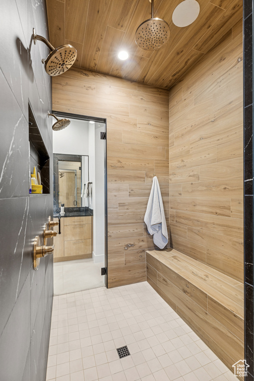 Bathroom with recessed lighting, tile patterned flooring, wooden walls, wood ceiling, and tiled shower