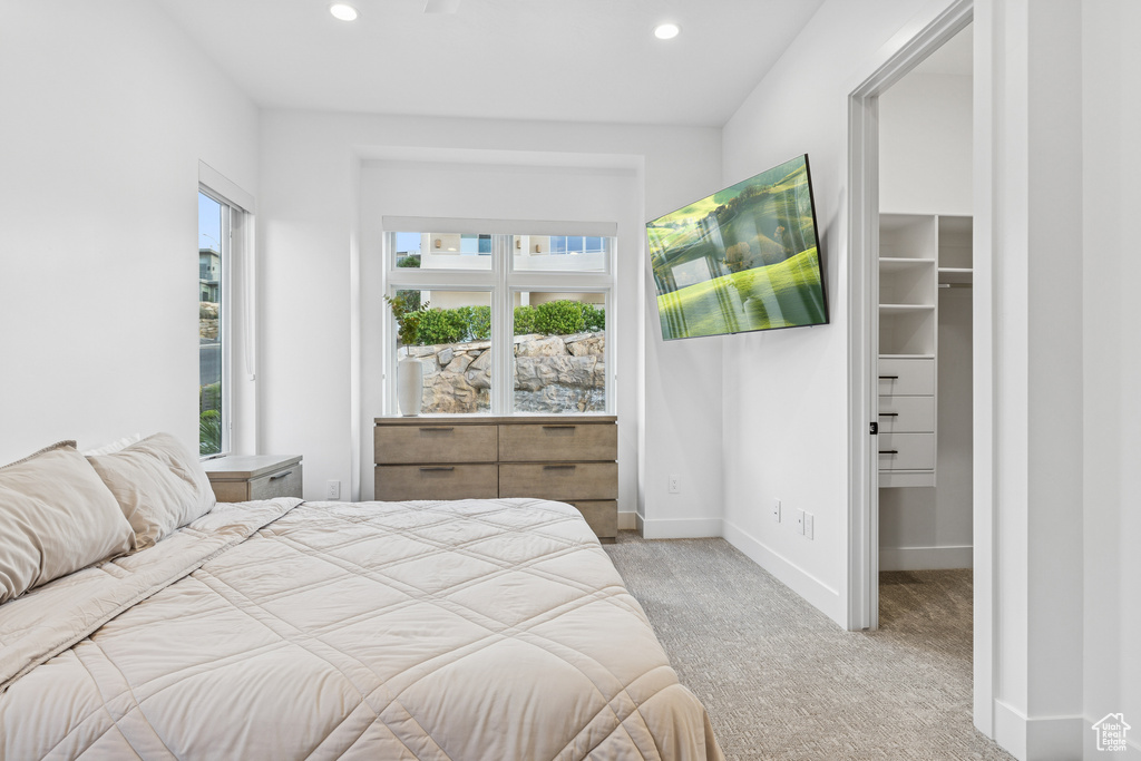 Carpeted bedroom with baseboards, recessed lighting, and a walk in closet