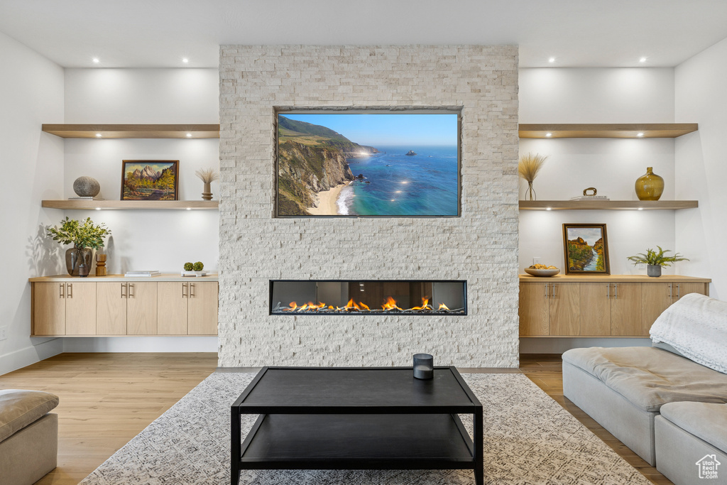 Living room featuring wood finished floors, a stone fireplace, and recessed lighting