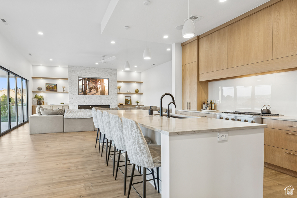 Kitchen featuring a large island with sink, modern cabinets, a breakfast bar, and a sink