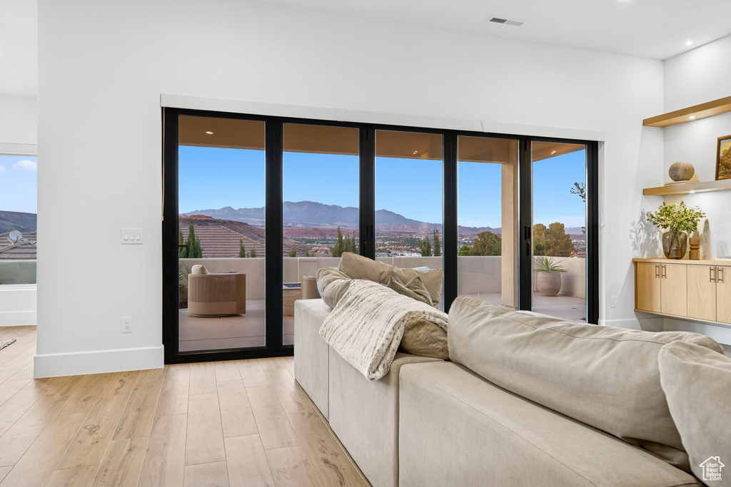 Living room featuring light wood finished floors, a mountain view, a wealth of natural light, and visible vents
