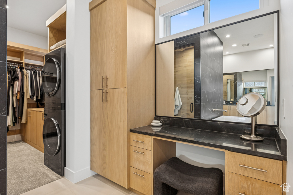 Bathroom featuring a wealth of natural light, a spacious closet, stacked washing maching and dryer, and vanity
