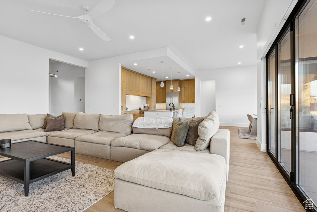 Living room featuring light wood-style flooring, visible vents, baseboards, ceiling fan, and recessed lighting