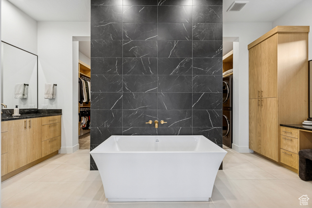 Full bathroom featuring stacked washer / drying machine, tile walls, an accent wall, vanity, and a spacious closet