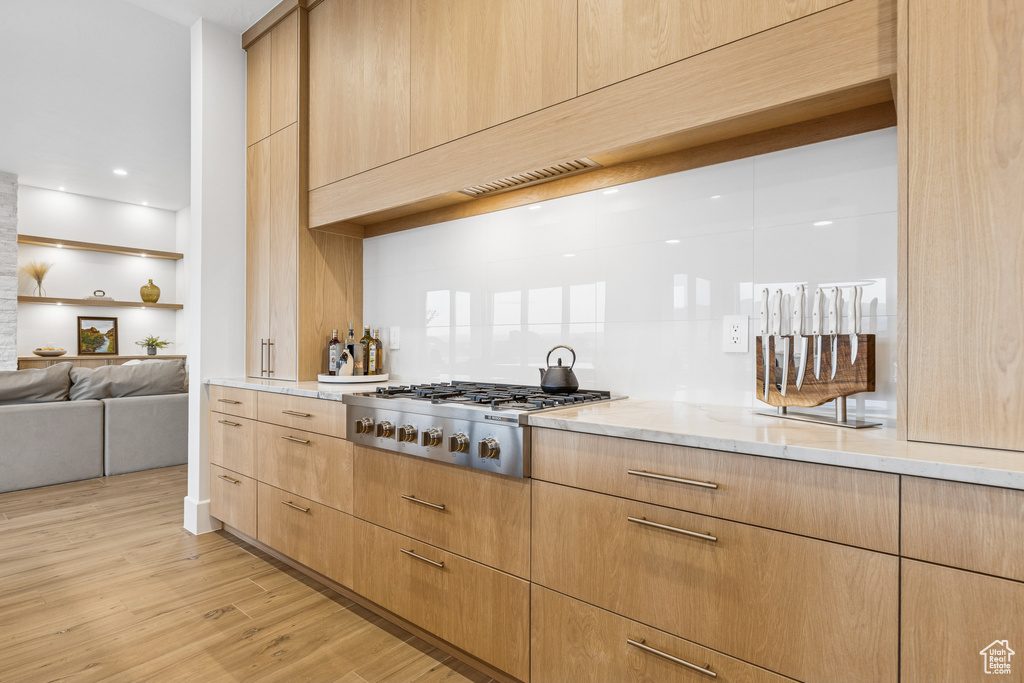 Kitchen featuring stainless steel gas cooktop, light wood finished floors, open floor plan, light brown cabinetry, and light stone countertops
