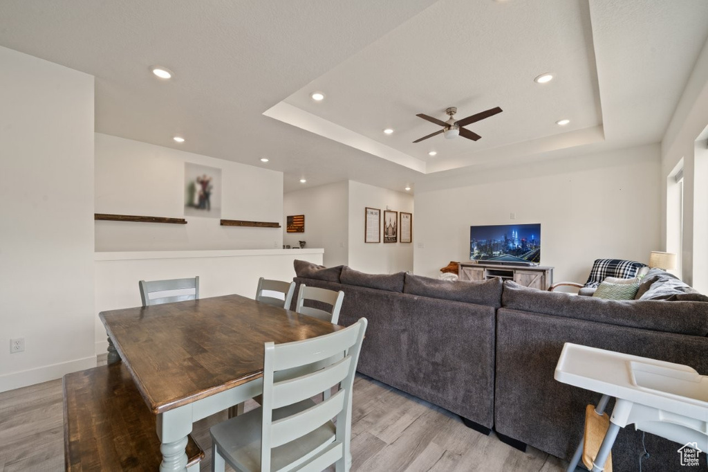 Dining area with a tray ceiling, light wood-style floors, a ceiling fan, and recessed lighting