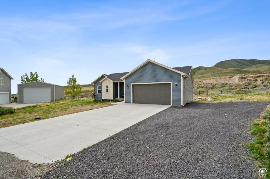 Ranch-style house featuring an attached garage, a mountain view, driveway, and fence