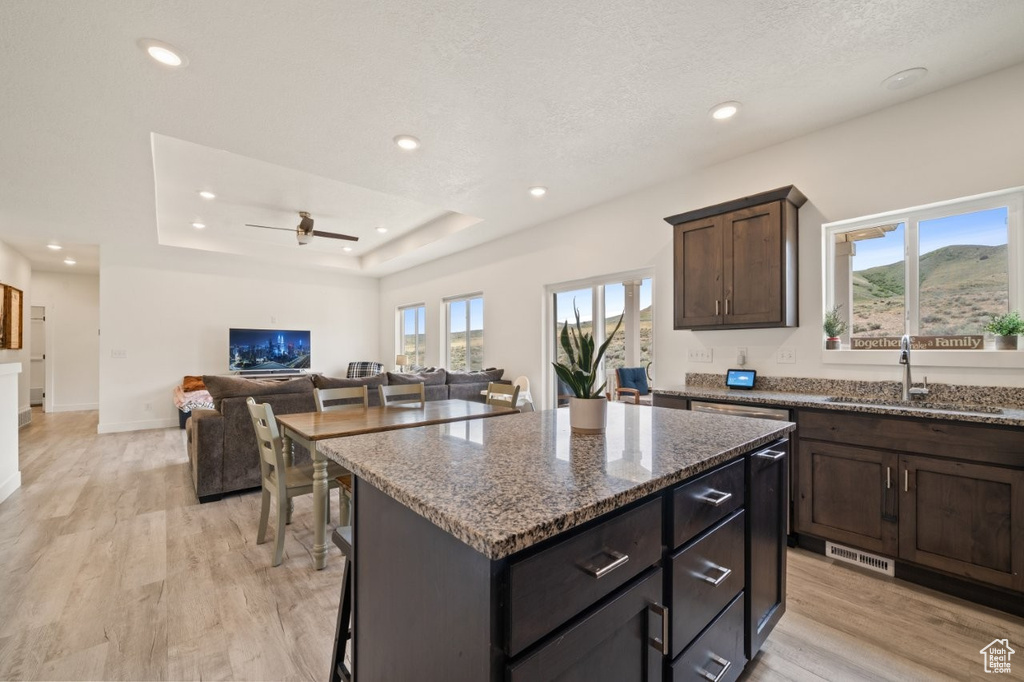 Kitchen featuring a sink, a center island, plenty of natural light, and stone counters