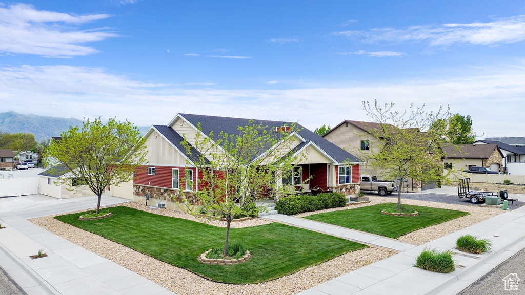 View of front of house featuring concrete driveway, a front lawn, a residential view, and stone siding
