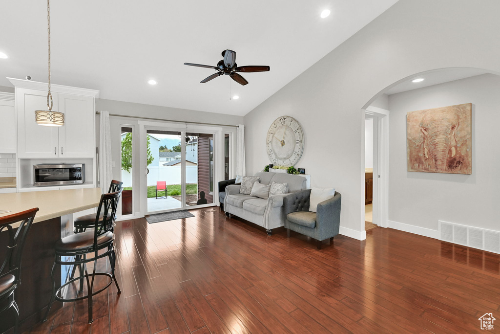Living area featuring visible vents, ceiling fan, arched walkways, lofted ceiling, and dark wood-style floors