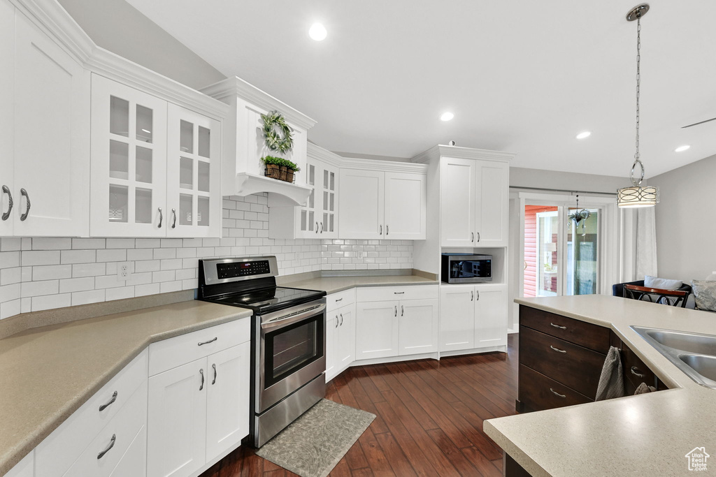 Kitchen featuring tasteful backsplash, light countertops, dark wood-style floors, glass insert cabinets, and appliances with stainless steel finishes