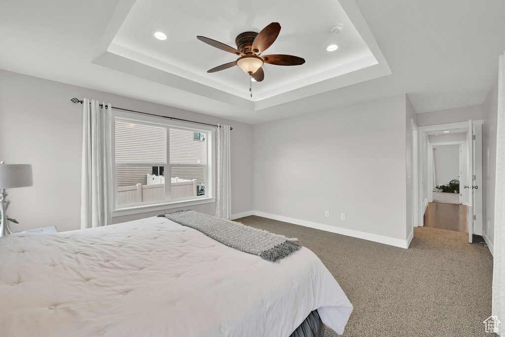 Carpeted bedroom with baseboards, a raised ceiling, recessed lighting, and a ceiling fan