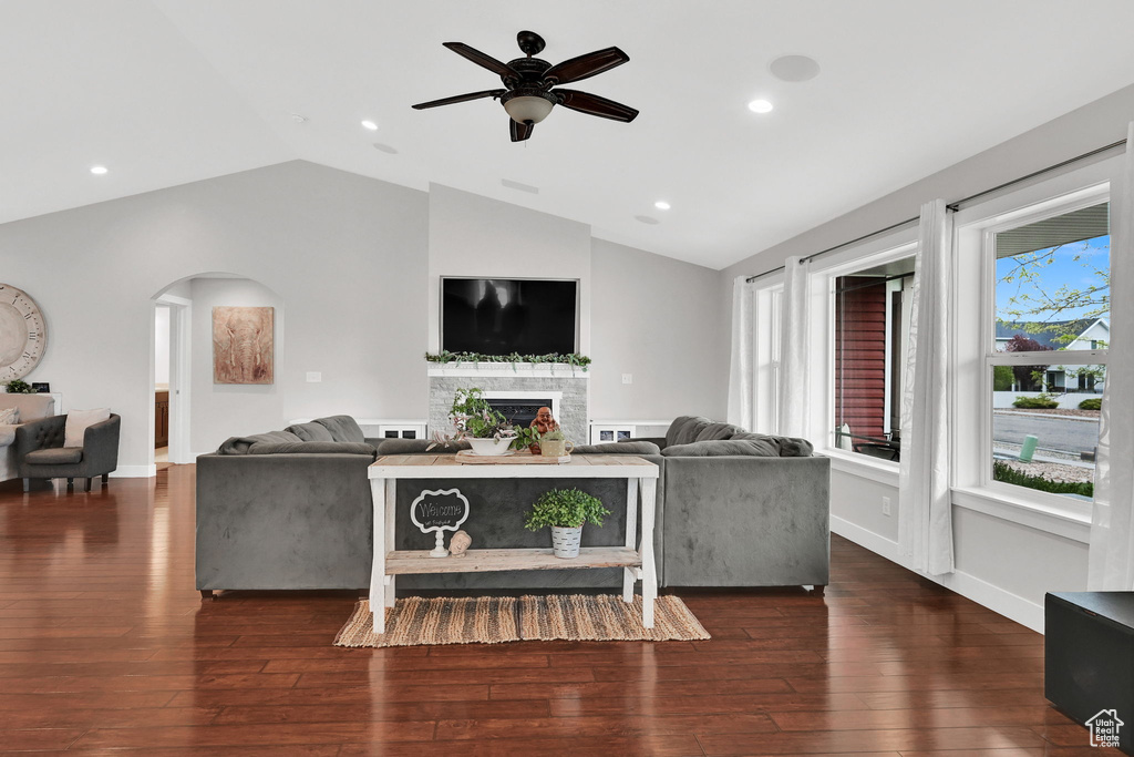 Living room featuring hardwood / wood-style floors, vaulted ceiling, a fireplace, and arched walkways