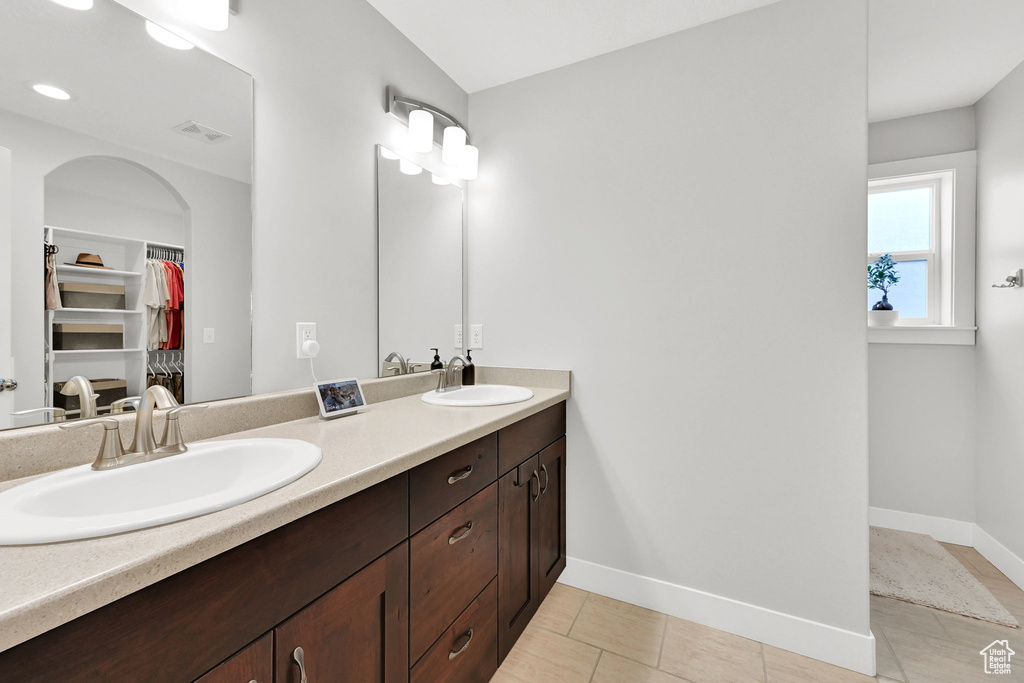 Bathroom with a sink, double vanity, a walk in closet, and visible vents
