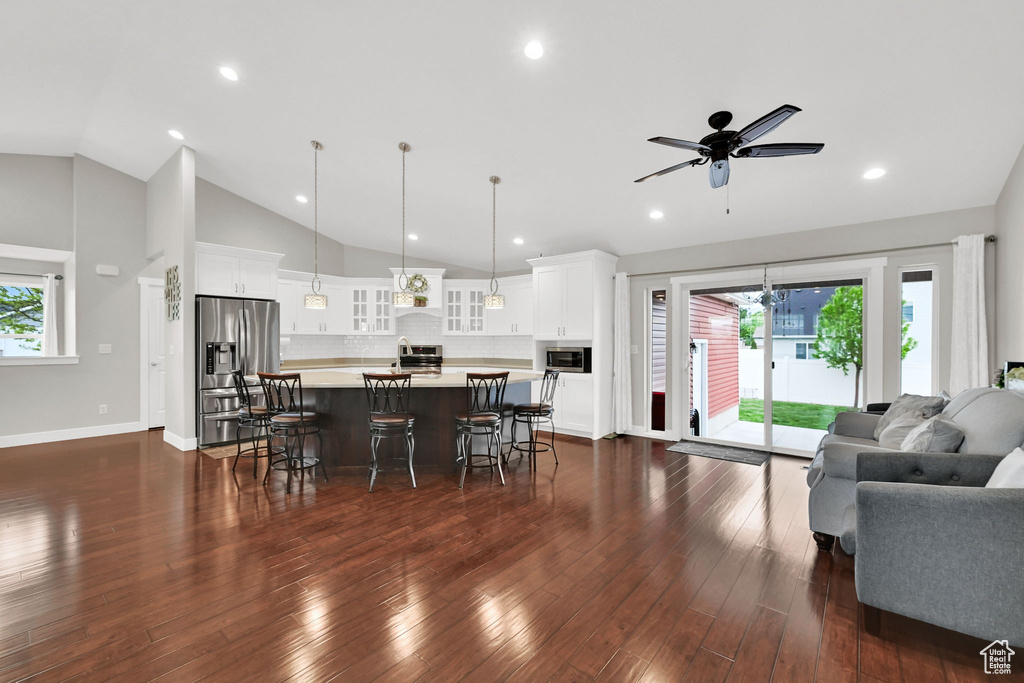 Living room featuring recessed lighting, vaulted ceiling, dark wood-style flooring, a ceiling fan, and baseboards
