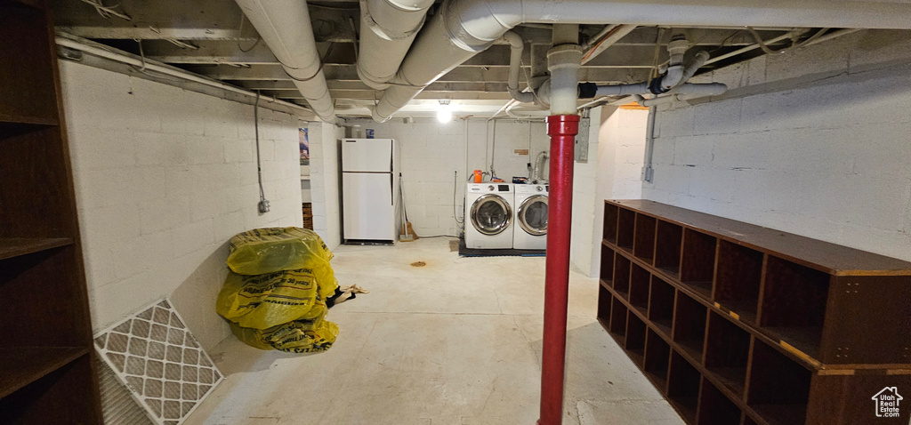 Unfinished basement featuring freestanding refrigerator and washer and clothes dryer