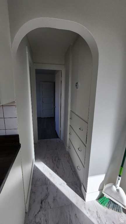 Hallway featuring arched walkways and marble finish floor