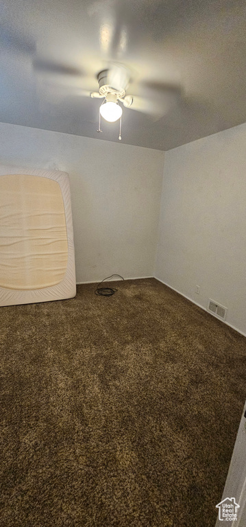 Carpeted empty room with visible vents and ceiling fan