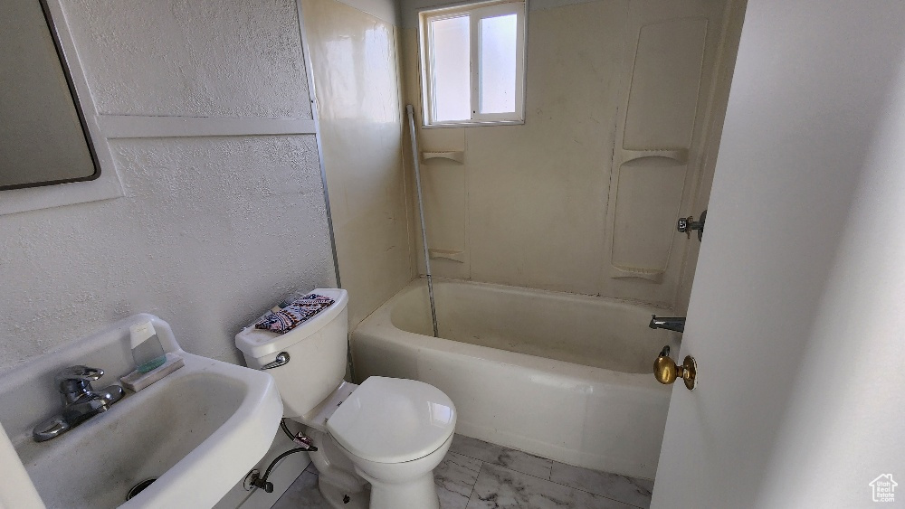 Full bath with toilet, shower / bathing tub combination, marble finish floor, and a sink
