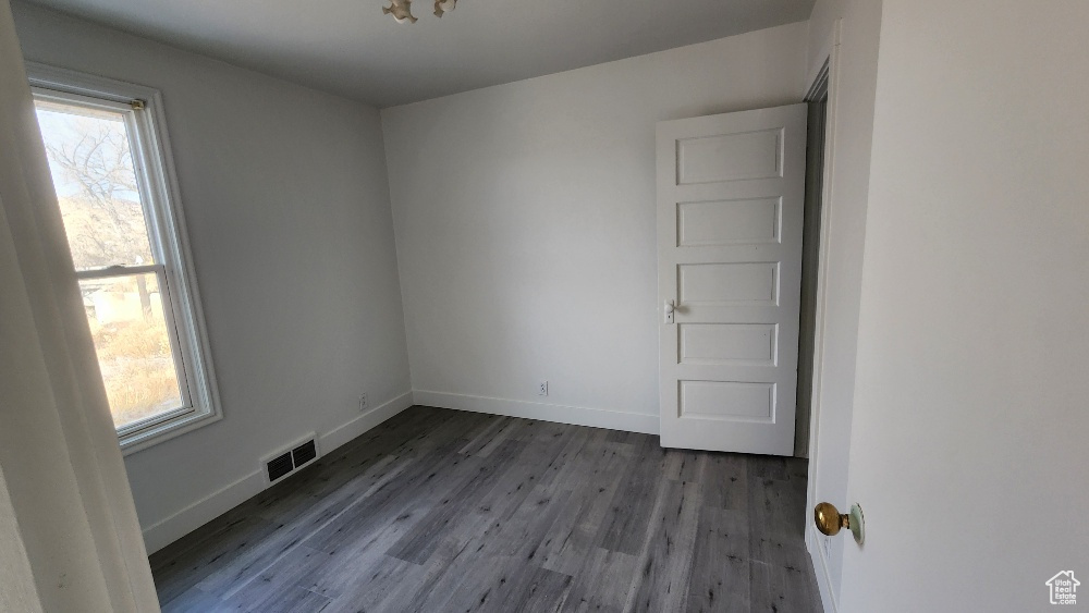 Unfurnished room featuring baseboards, visible vents, and wood finished floors