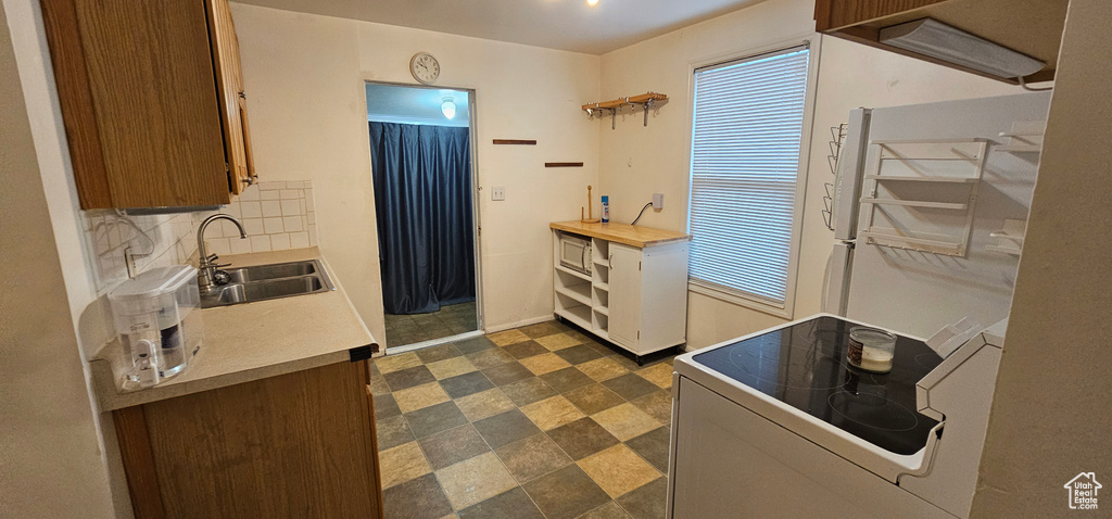 Kitchen with light countertops, tasteful backsplash, electric stove, and a sink