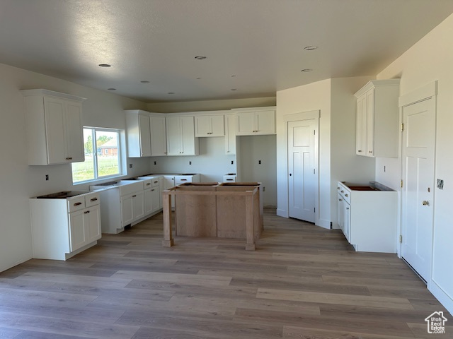 Kitchen with white cabinets, recessed lighting, light wood-style flooring, and a center island