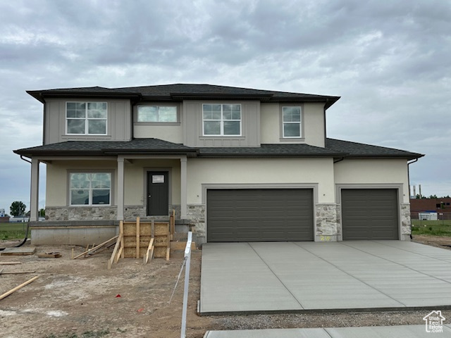 Prairie-style home featuring concrete driveway, an attached garage, stucco siding, and stone siding