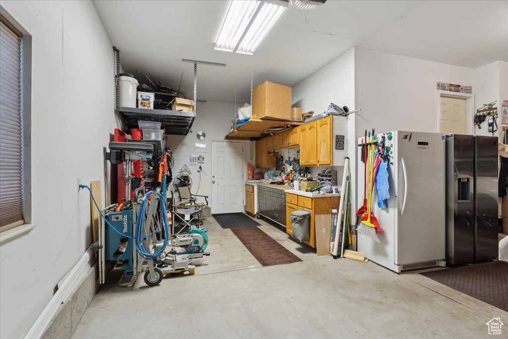 Garage featuring freestanding refrigerator, a workshop area, and black fridge