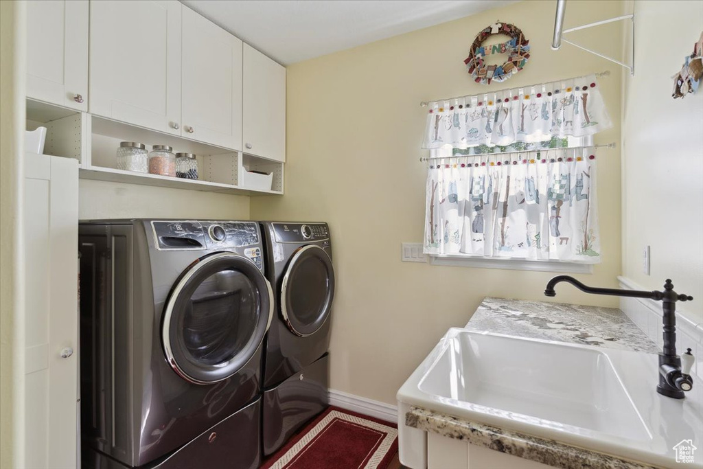 Laundry room featuring a sink, separate washer and dryer, cabinet space, and baseboards