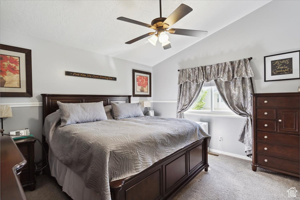 Carpeted bedroom with ceiling fan, lofted ceiling, and baseboards