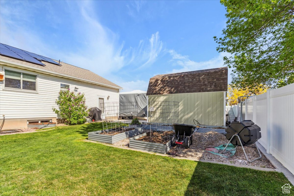 View of yard featuring a fenced backyard, a storage shed, a vegetable garden, and an outbuilding