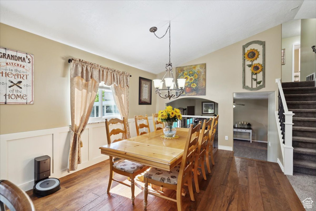 Dining area with a notable chandelier, stairway, vaulted ceiling, and hardwood / wood-style flooring