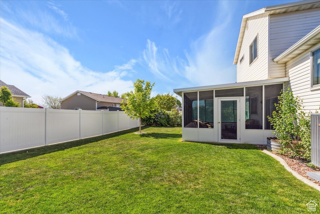 View of yard featuring a sunroom and fence
