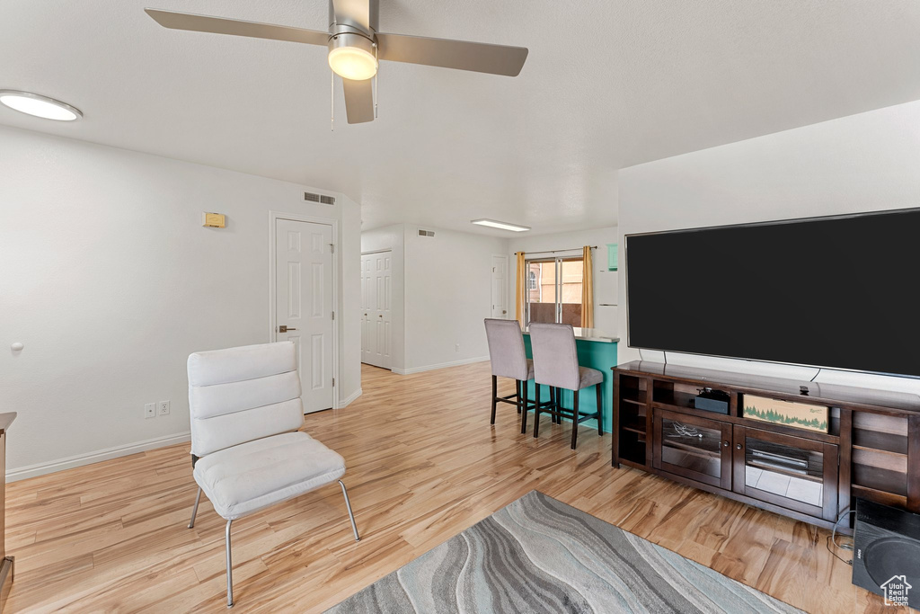 Living area featuring a ceiling fan, baseboards, visible vents, and light wood-style flooring