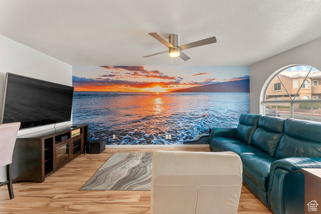 Living room with a water view, ceiling fan, and wood finished floors