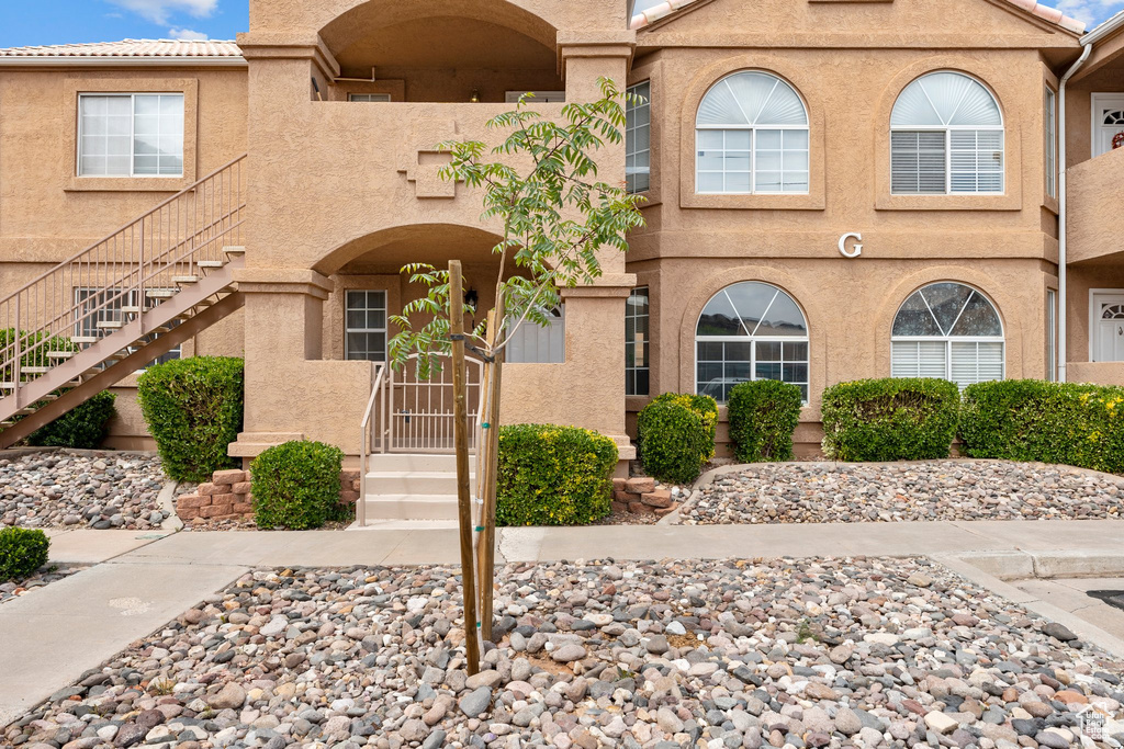 View of front of house featuring stairway and stucco siding