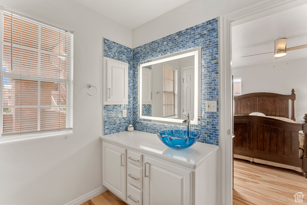 Bathroom with vanity, a wealth of natural light, wood finished floors, and tasteful backsplash