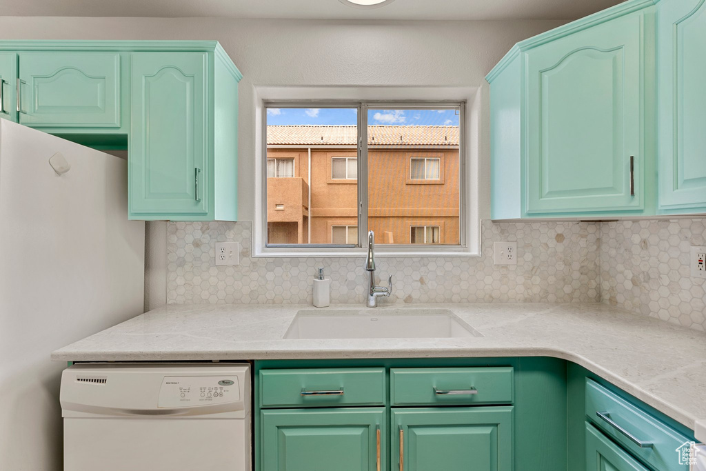 Kitchen with white appliances, light countertops, a sink, and tasteful backsplash