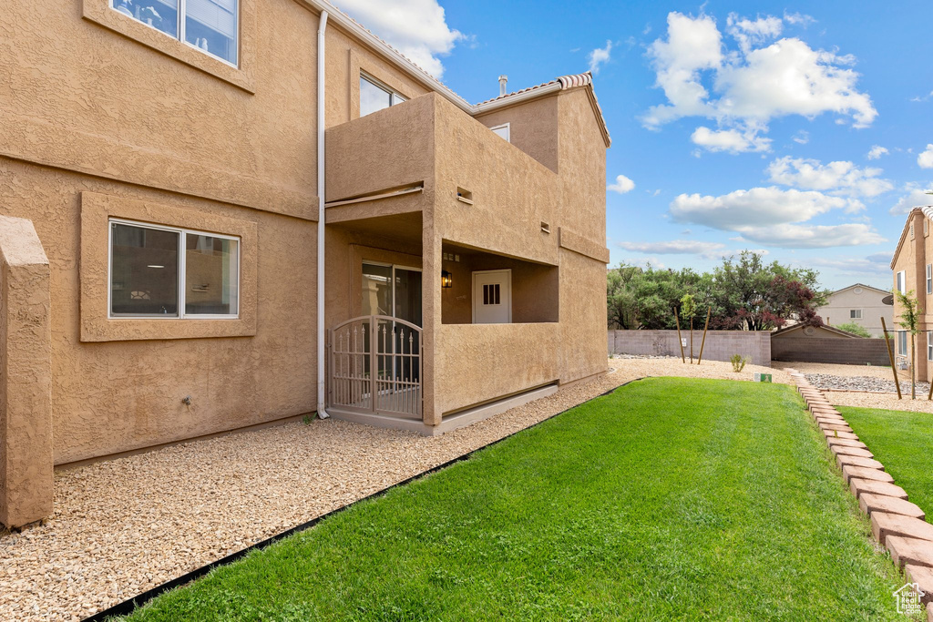Rear view of property with a lawn, fence, and stucco siding