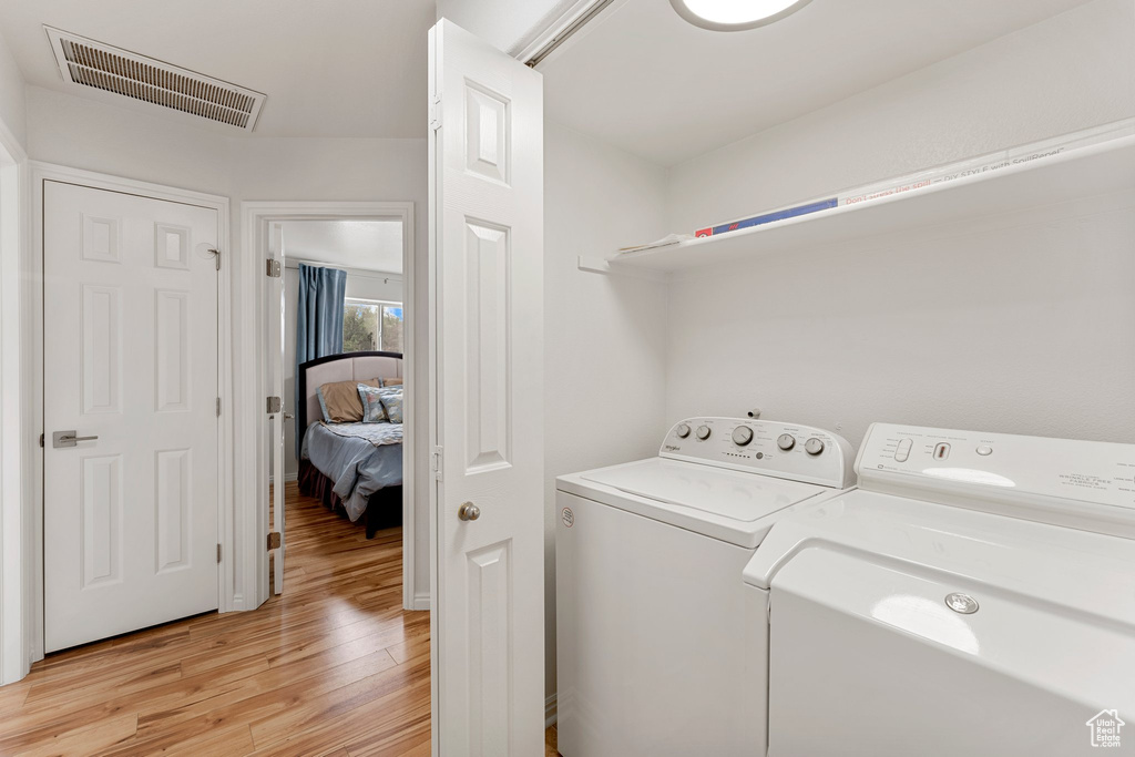 Clothes washing area featuring independent washer and dryer, laundry area, visible vents, and light wood finished floors