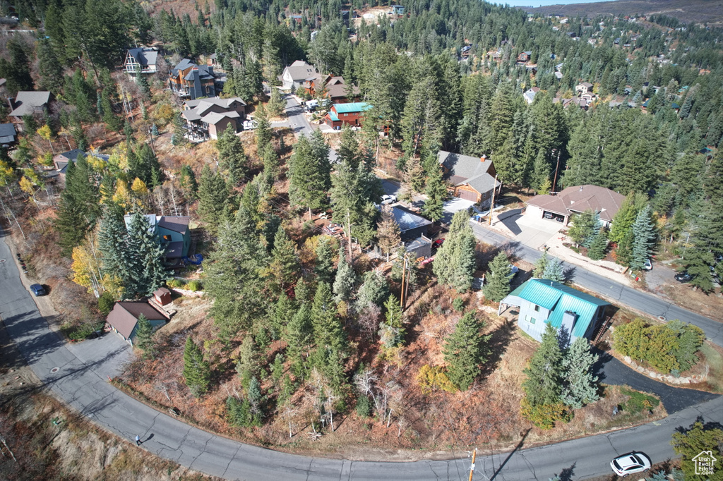 Aerial view of property and surrounding area featuring a forest and nearby suburban area