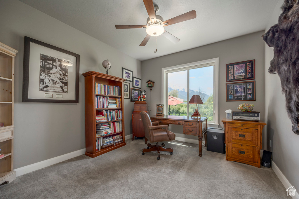 Carpeted office space featuring a ceiling fan and baseboards