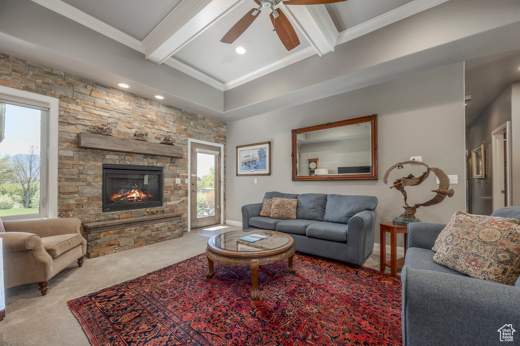 Living area featuring carpet flooring, a ceiling fan, a fireplace, beamed ceiling, and ornamental molding