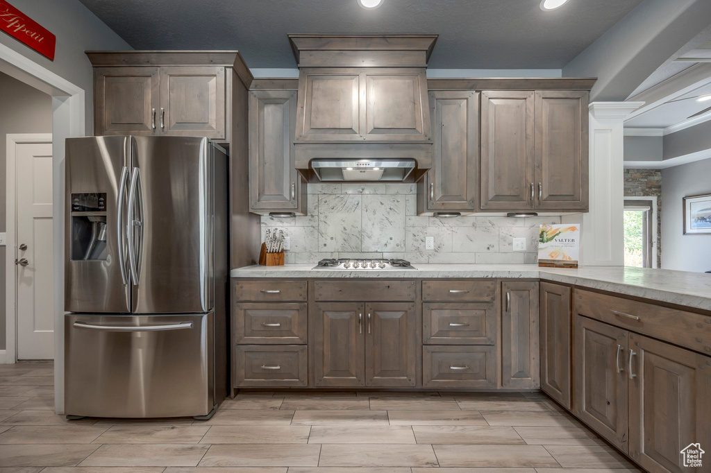 Kitchen with recessed lighting, custom range hood, wood finish floors, backsplash, and stainless steel appliances