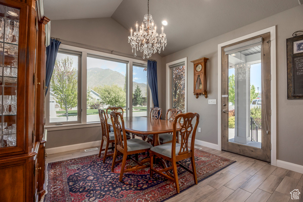 Dining space featuring a mountain view, baseboards, a chandelier, vaulted ceiling, and light wood-type flooring