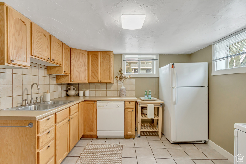 Kitchen featuring a sink, white appliances, light countertops, tasteful backsplash, and light tile patterned flooring