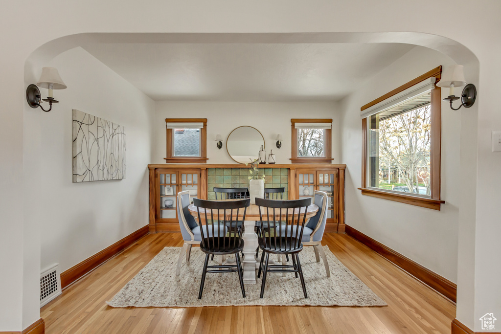 Dining room with arched walkways, baseboards, visible vents, and wood finished floors
