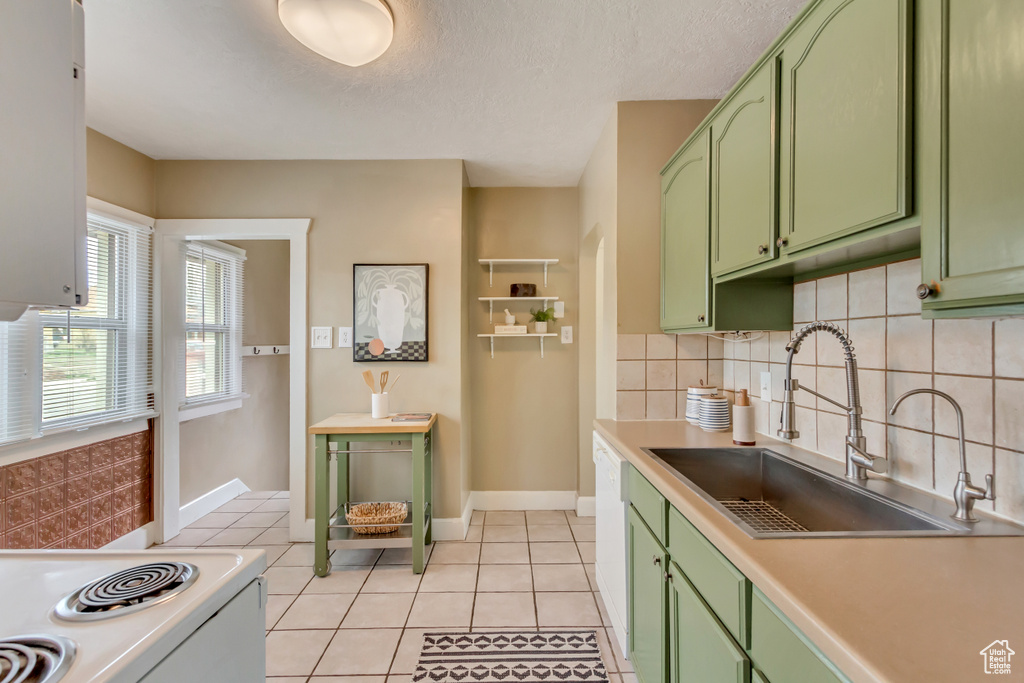 Kitchen featuring white appliances, a sink, green cabinetry, light countertops, and tasteful backsplash