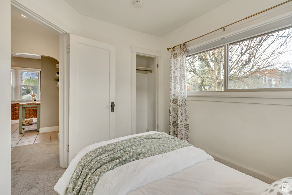 Bedroom featuring a closet, carpet floors, baseboards, arched walkways, and wine cooler
