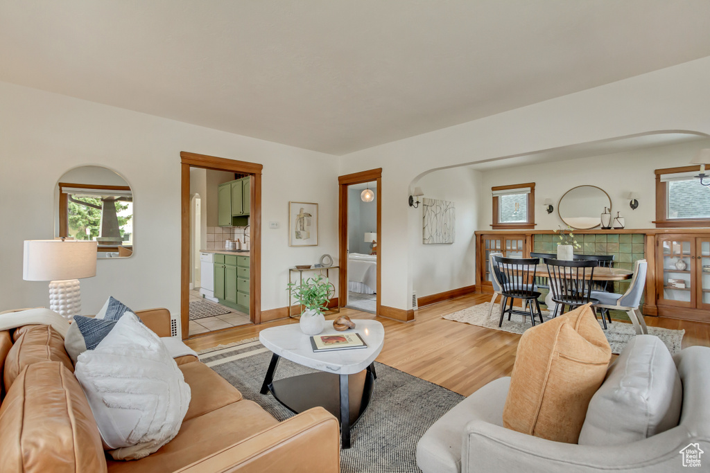 Living room featuring arched walkways, a healthy amount of sunlight, and light wood-type flooring